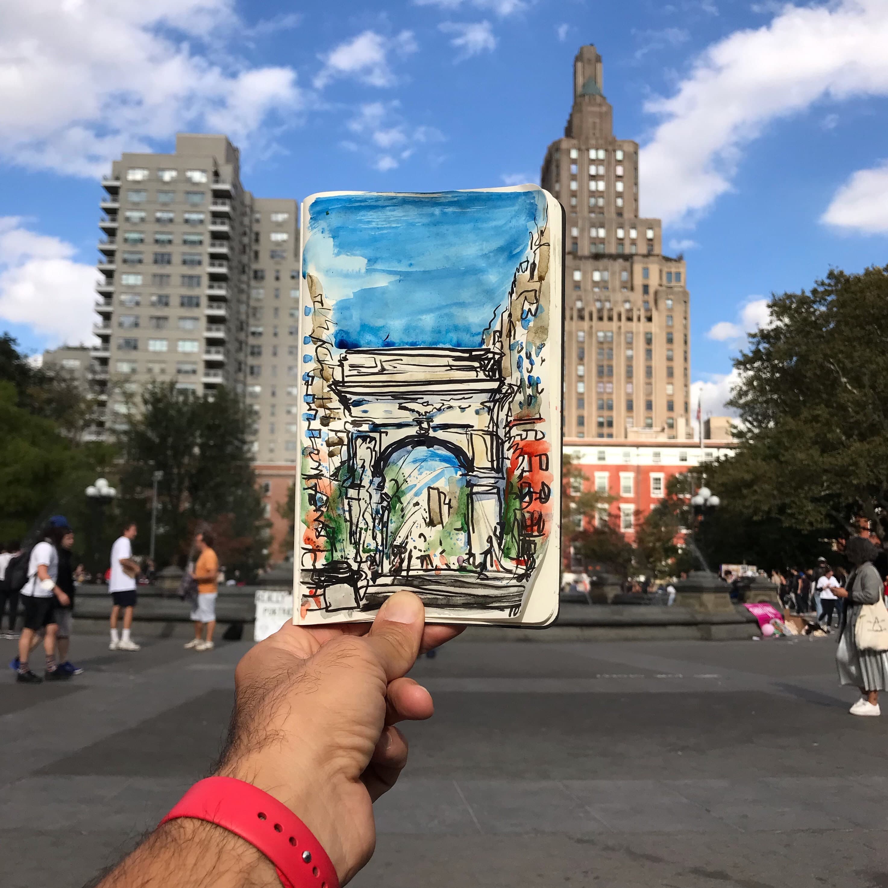 Watercolor sketch of Washington Square Park held up in front of the scene in the park.